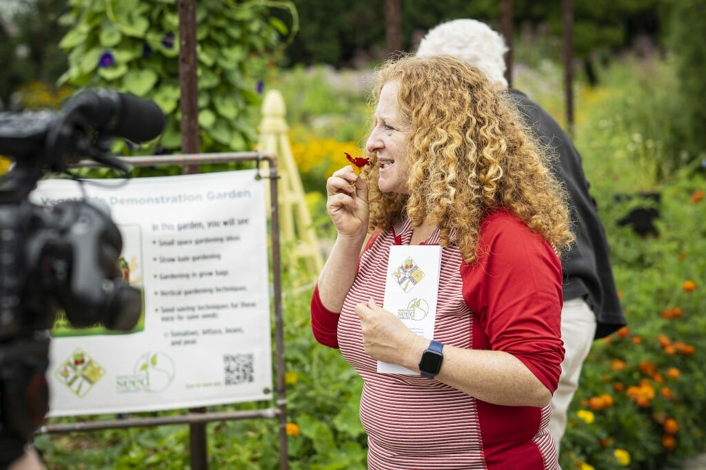Chancellor Mnookin tastes an edible flower at the Garden Door public gardens at the UW Peninsular Agricultural Research Station.