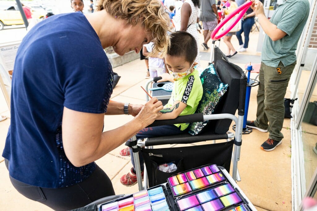 A person paints on a child's arm.