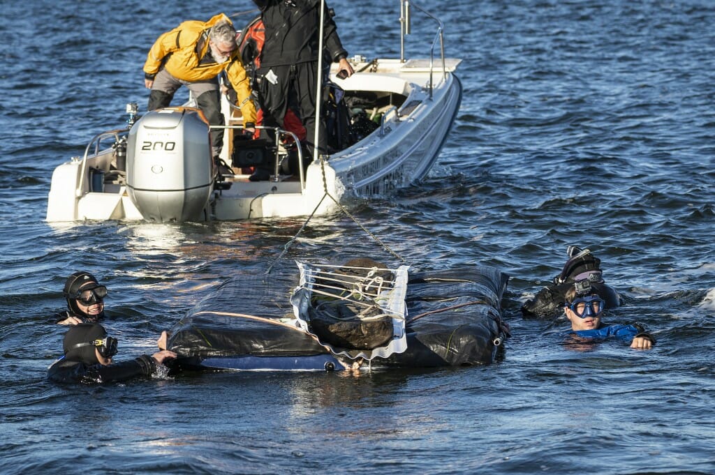 Divers stabilize a raft during the recovery of the canoe.