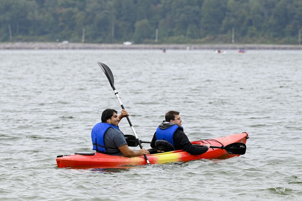 Two young people share a kayak on a lake