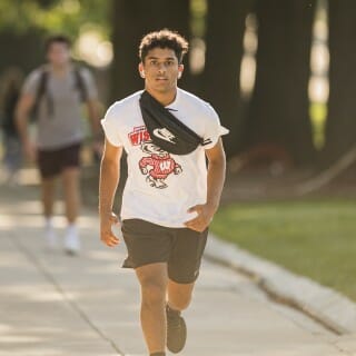 A man wearing a Bucky Badger t-shirt runs up a hill.