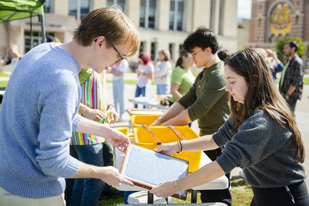 Andie Barrow and a student hold each end of a paper making screen while talking about the paper making process.