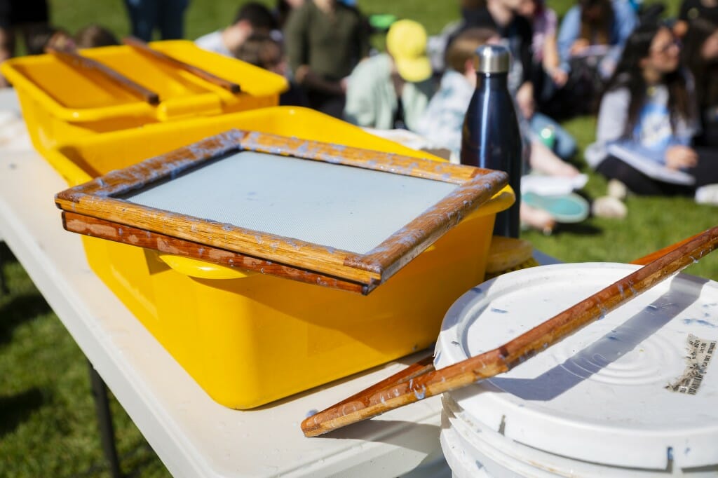 Yellow tubs and paper making screens sit on a white table.