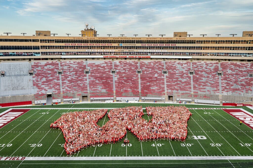 First-year students, along with UW mascot Bucky Badger and Chancellor Mnookin, form the shape of an iconic Motion W as part of the W Project on Barry Alvarez Field at Camp Randall Stadium.
