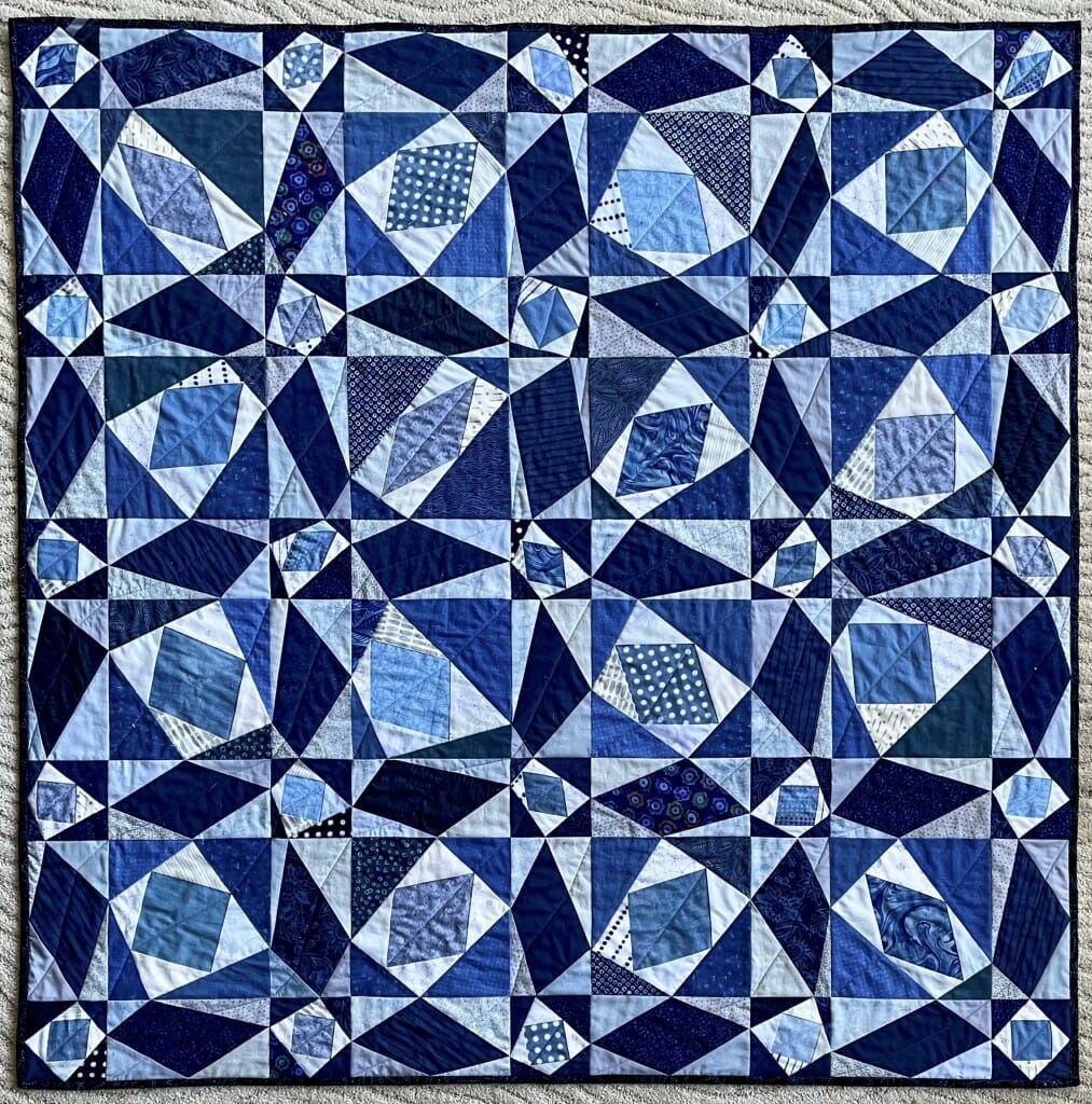 Follow this mathematical thread: The perfect regularity and symmetry of the traditional “Storm at Sea” patchwork has been disrupted in this quilt by shifting, in tandem, neighboring corners of the four-sided shapes in white and navy blue, placing the pairs of offset corners at a random position along the edge of the square or rectangle in which the quadrilaterals are inscribed. The 41 light blue quadrilaterals connect the midpoints of the edges of the white asymmetric quadrilaterals, and each is a visual illustration of Varignon’s Theorem, which proves that its shape must be a parallelogram.
 Amy Wendt,
professor, Electrical and Computer Engineering
machine pieced and quilted cotton fabric