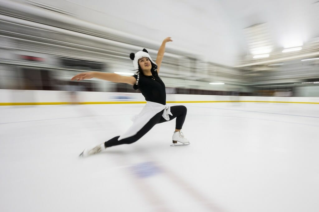 A person in a panda costume skates while dramatically extending her arms.