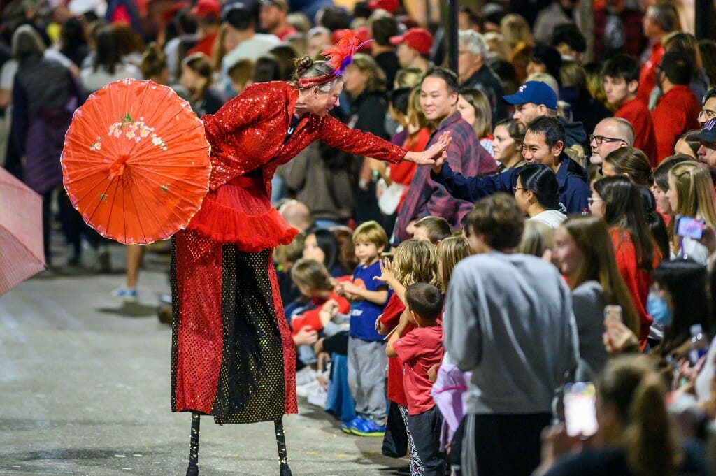 A sequin-clad stilt walker with Wild Rumpus Circus gives a high five to a spectator.