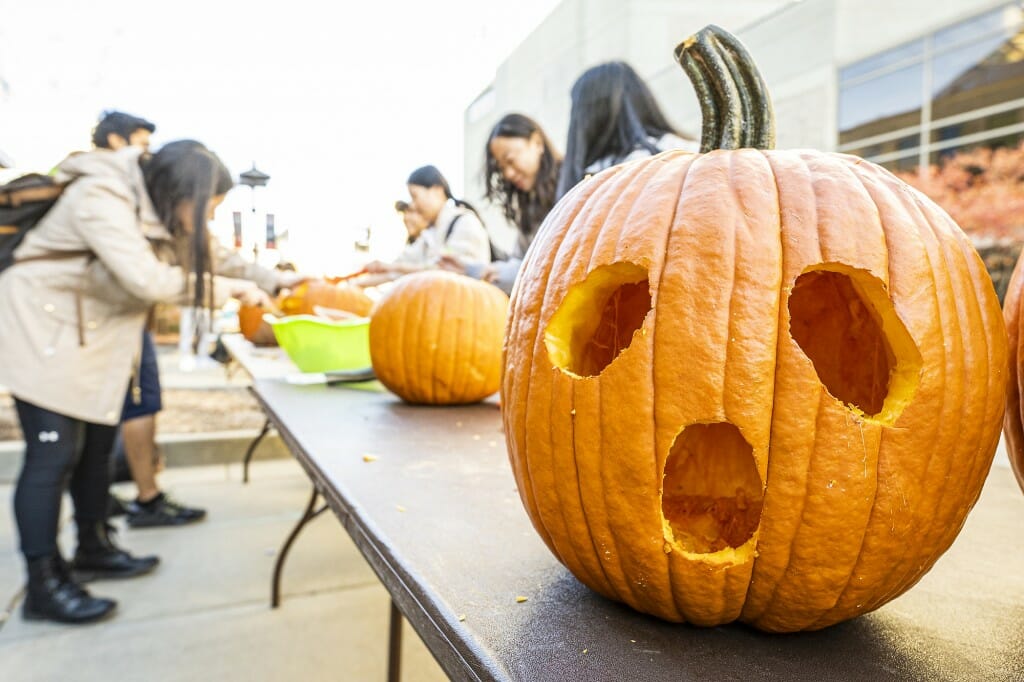 A carved pumpkin with a wide open mouth and circular eyes.