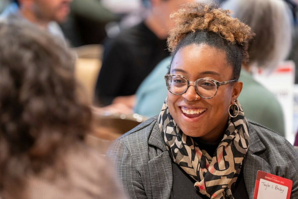 A woman smiles and talks with others.