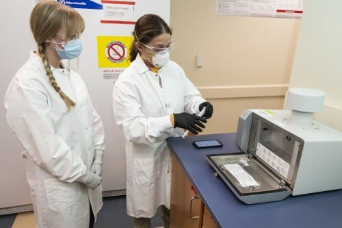 Shelby O’Connor (right) shows research assistant Olivia Harwood how to load a collection sample into a device