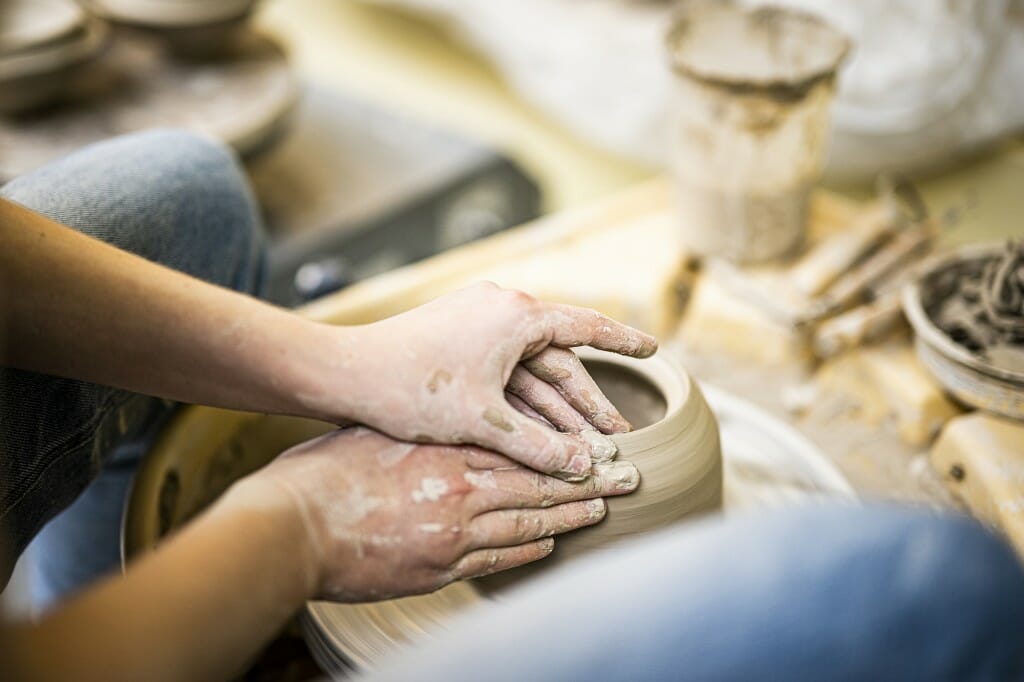 Some hands on a piece of pottery on a wheel.