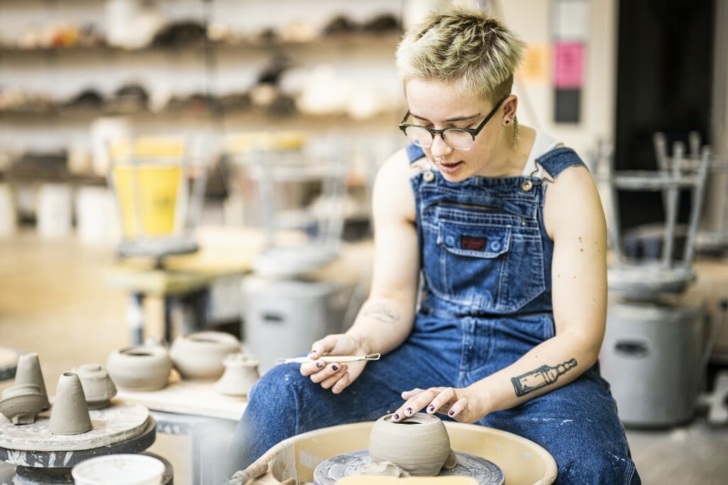 Undergraduate ceramics student Eli Johnson crafts a wheel-thrown container.
