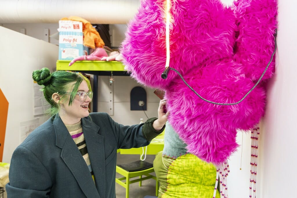 A woman adjusts a plush figure in bright pink.