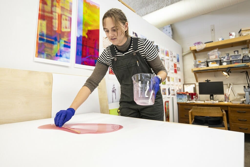 A woman manipulates some resin on a table.