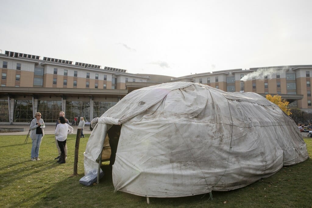 A canvas covered structure sits on a lawn.