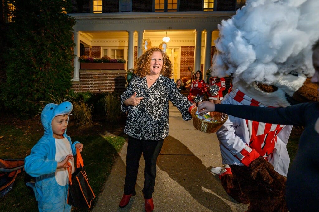 Chancellor Jennifer Mnookin stands in front of Olin House handing out candy to trick-or-treaters.
