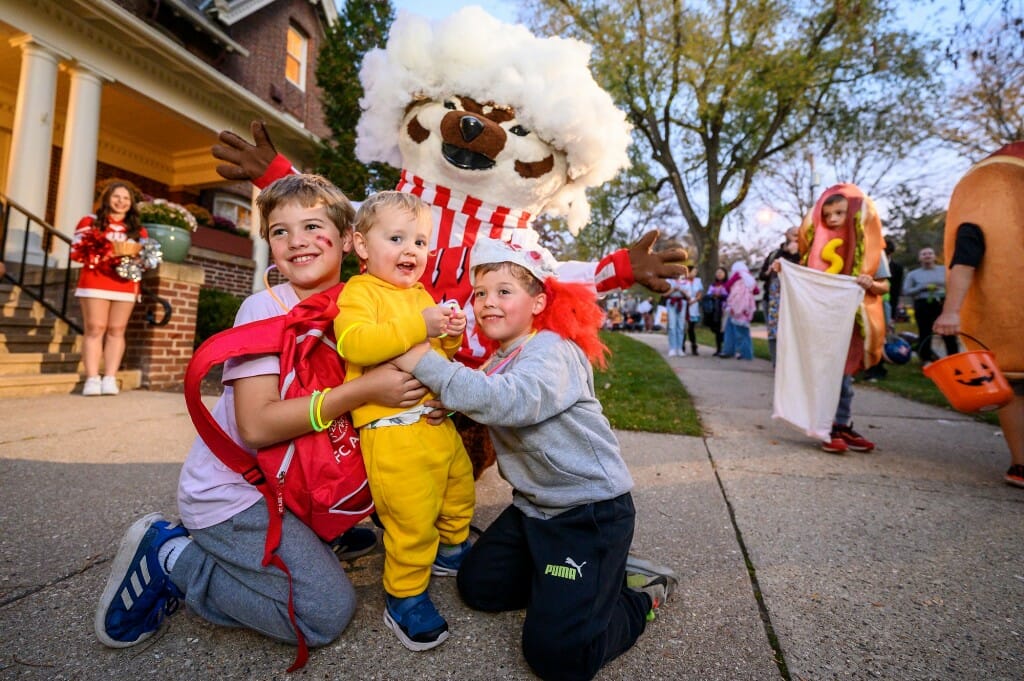 Three young trick-or-treaters pose with Bucky Badger outside of Olin House.