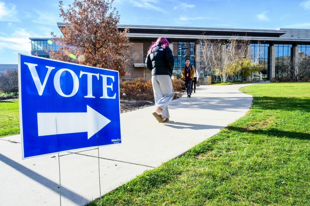 Pedestrians walk by a voting sign in front of the Gordon Dining & Event Center at the University of Wisconsin-Madison
