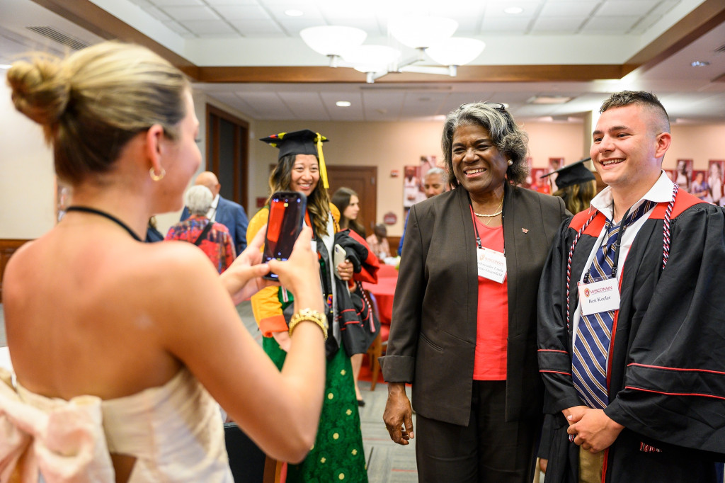 A student uses her phone to take a photo of Ben Keeler posing with Linda Thomas-Greenfield at a commencement luncheon.