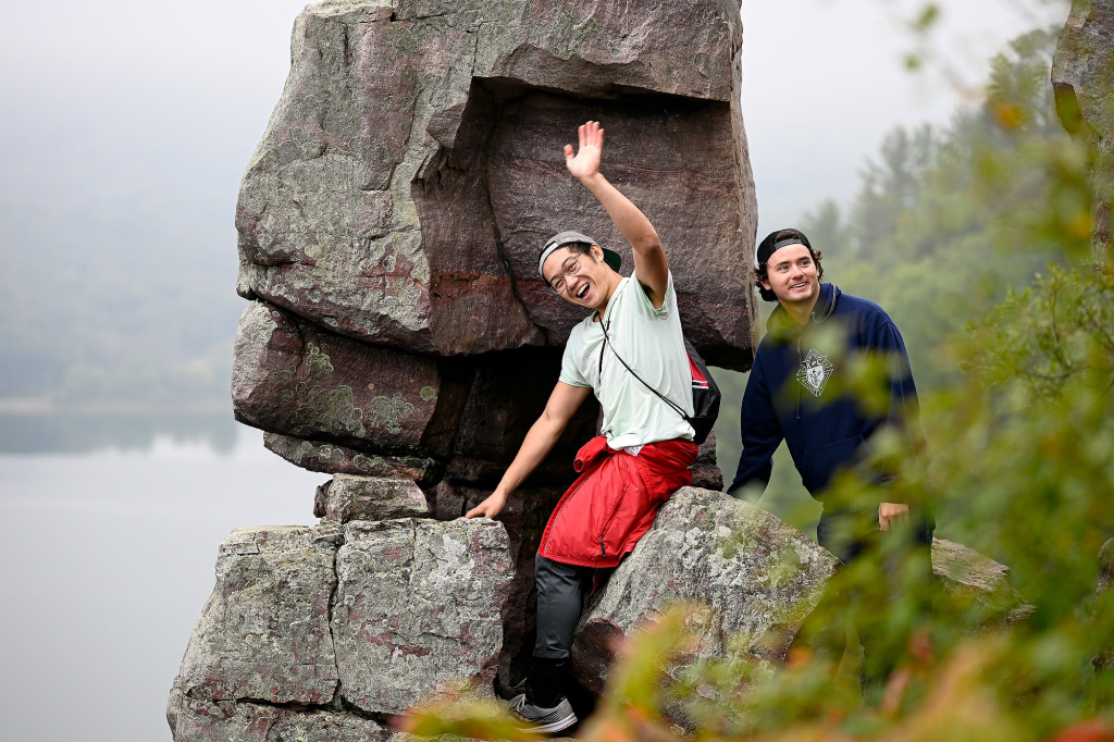 Two students smile toward the camera while perching on Balanced Rock at Devil’s Lake State Park on a misty fall day.