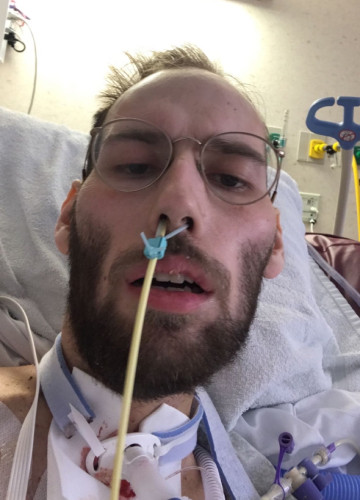 A selfie photo of a man lying in a hospital bed, oxygen tube in his nose.