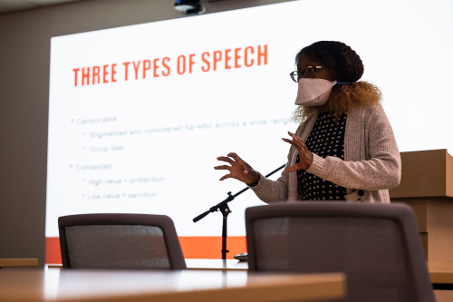 Franciska Coleman speaks to an unpictured audience in front of a screen with a slide reading "Three types of speech."