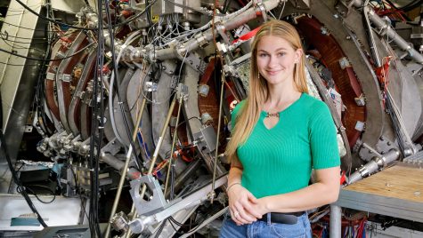 Grace Stanke pictured with the HSX fusion experiment at UW–Madison.