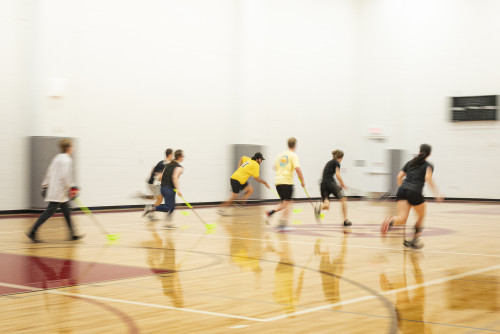 A blurred action shot of two teams running down a floorball court