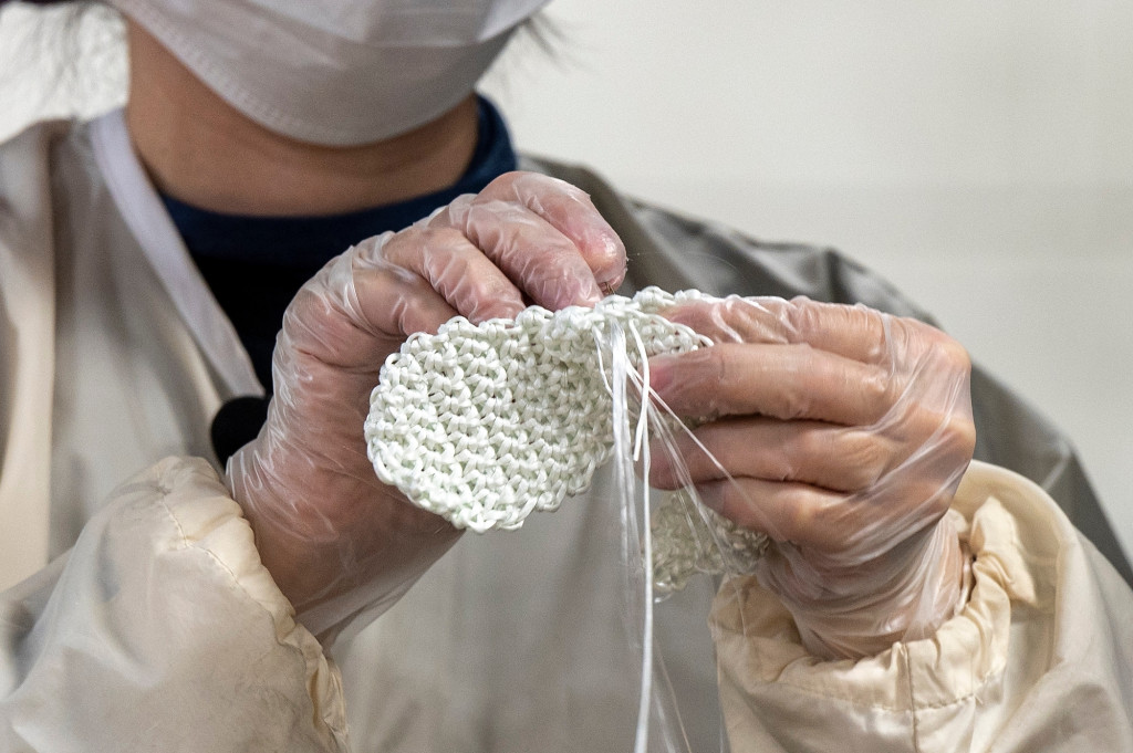 Closeup of Machiko Ito stitching two crocheted fiberglass pieces together.