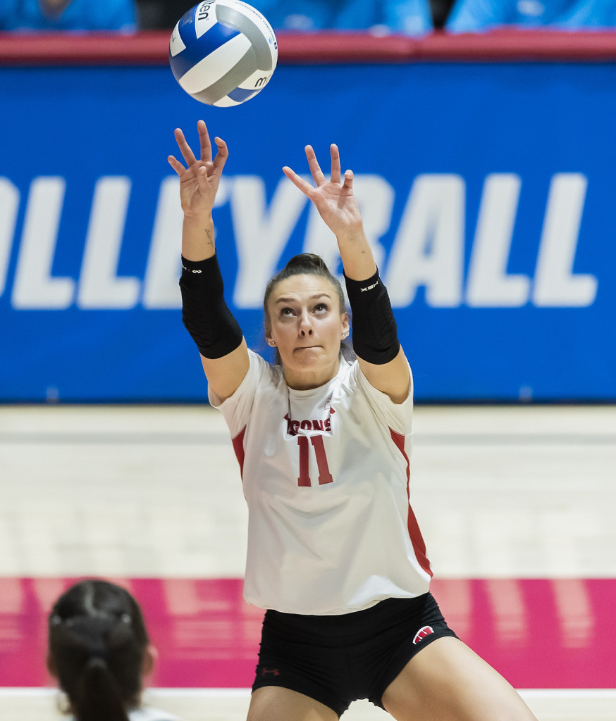 A volleyball player stretches her arms out to strike the ball.