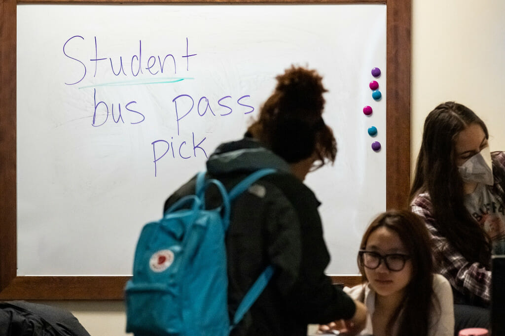 A person stands in line in front of a white board reading 
