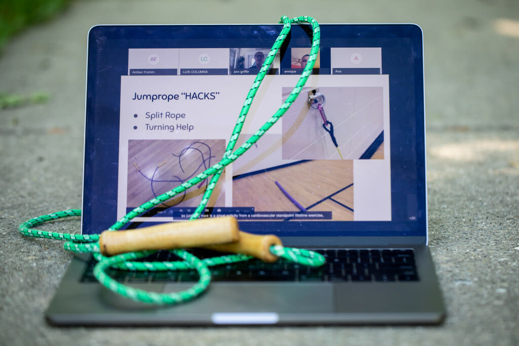 An open laptop showing an exercise regemin. A green jumprope lies on the keyboard.
