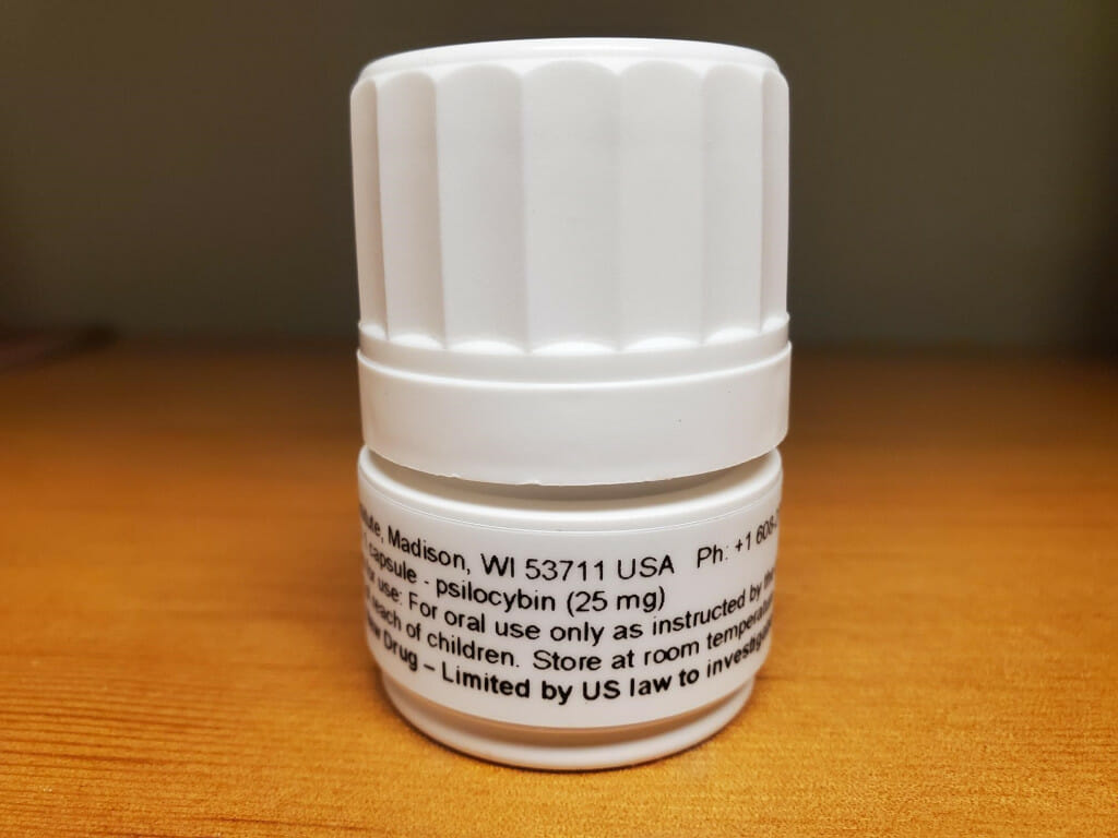 A close-up shot of a psilocybin prescription bottle sitting on a wooden table