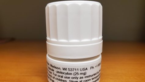 A close-up shot of a psilocybin prescription bottle sitting on a wooden table