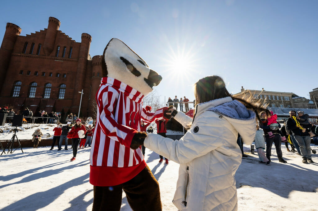 Bucky Badger dances with a fan during a Family Fun Day event, hosted by the Wisconsin Alumni Association and held at Alumni Park as part of Winter Carnival.