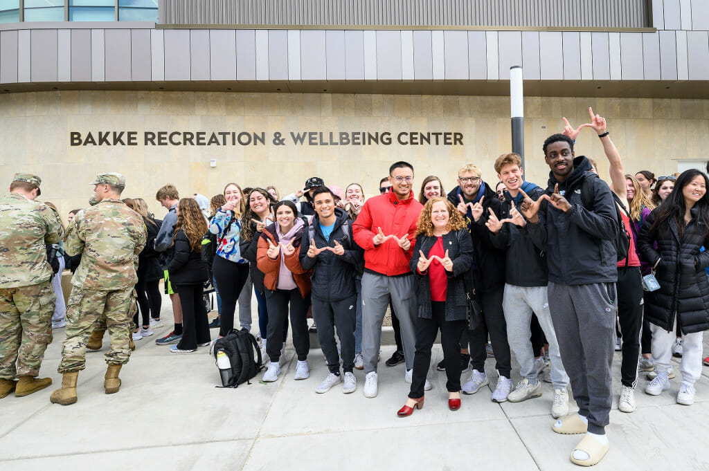 A group of people stand at the entrance to a new building, smiling.