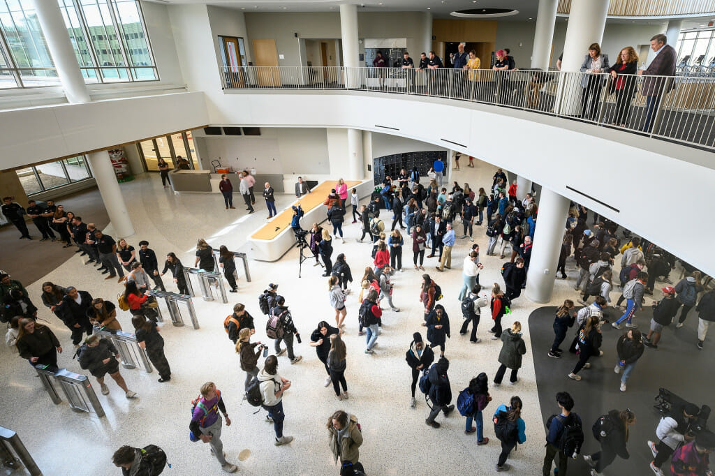 People on an upper floor look down on the main floor, crowded with students.