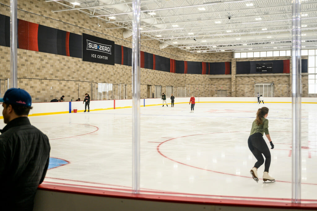 Several people skate on a brand-new ice surface.