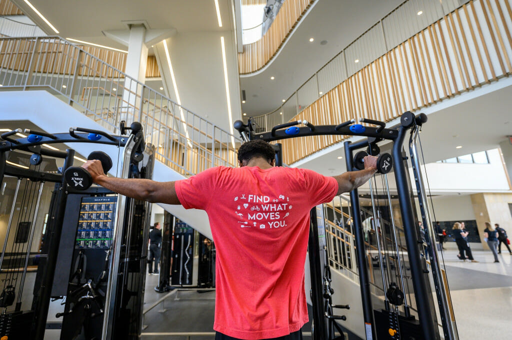 A person wearing red lifts a barbell.