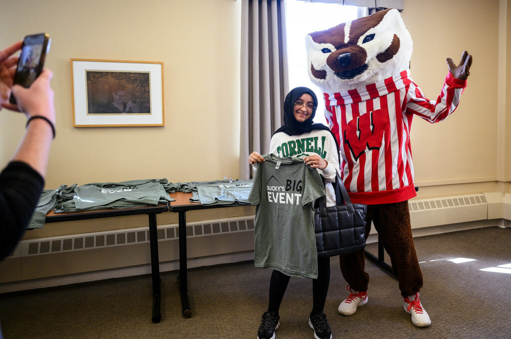 Undergraduate student Rawan Alnakhli poses with Bucky Badger as she picks up a t-shirt before volunteering at Rooted Farms as part of Bucky’s Big Event.
