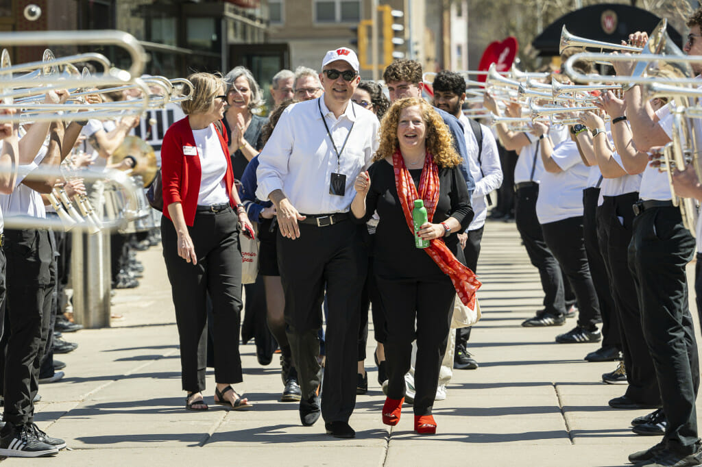 UW Chancellor Jennifer Mnookin and her husband, Professor Joshua Foa Dienstag, walk through a line of UW Marching Band members playing after the investiture ceremony.