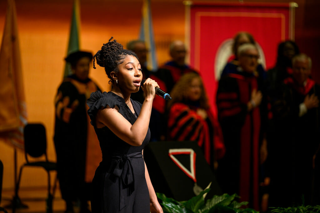 A woman holds a microphone and sings.