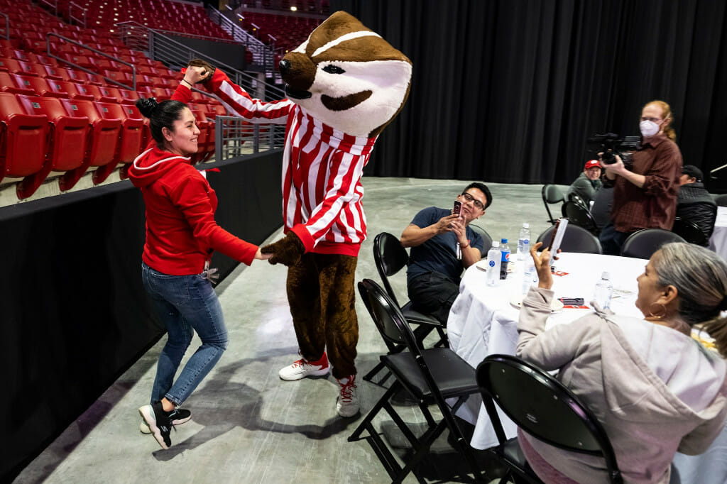 Elvira Martinez dances the polka with Bucky Badger while colleagues laugh and take photos.