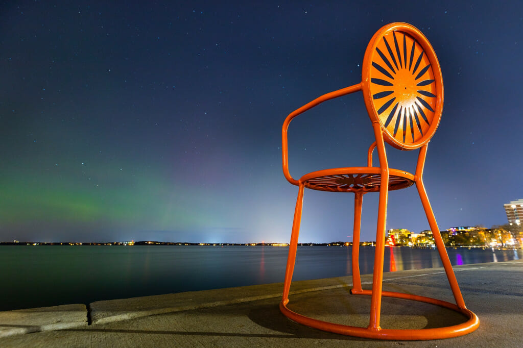 An orange chair with sunburst pattern contrasts with the green lights in the sky.