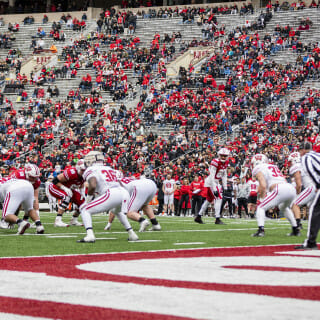 With football players in the foreground, the stands in the background are filled with fans wearing red and white.