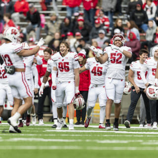 Football players in white jerseys raise their arms and celebrate.