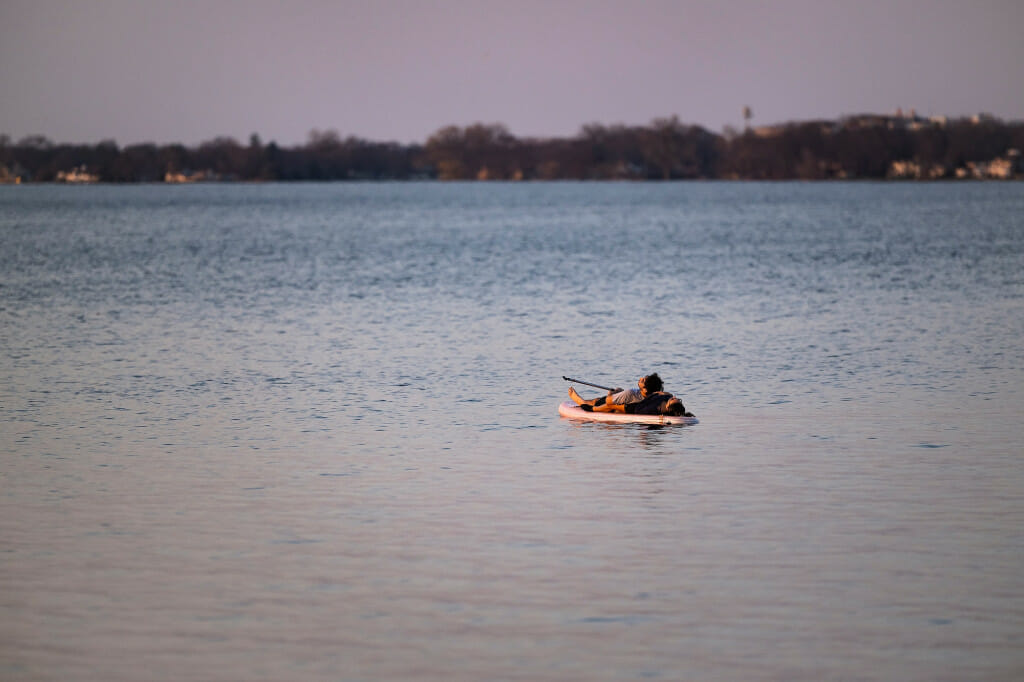 A couple lies on a paddle board on Lake Mendota, late on Monday.