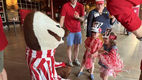 Bucky Badger greets some young kids wearing Wisconsin themed clothes.