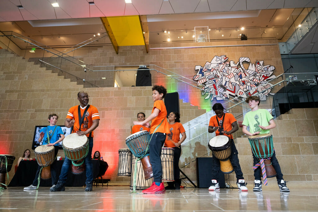 UW–Madison’s Dr. Yorel Lashley (second from left) and youth members of Drum Power perform at the start of a “re:mancipation” exhibit celebration.