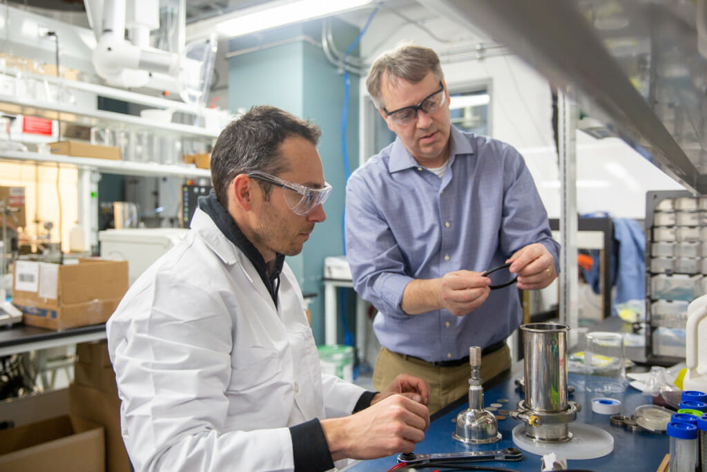 Troy Runge, Professor in the Biological Systems Engineering in CALS, and Jordi Francis, discuss engineering concerns in his lab at the WIsconsin Energy Institute.